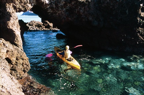 kayaker in small boat going through arch. 