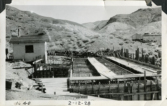 This is an historic black and white photograph from the Scotty's Castle Historic Photograph Collection, Death Valley National Park of Scotty's Castle Hacienda, looking east. First floor flat room rebar in place before concrete poured. Fire Cache on left. February 12, 1928. Photographed by Mat Roy Thompson.
