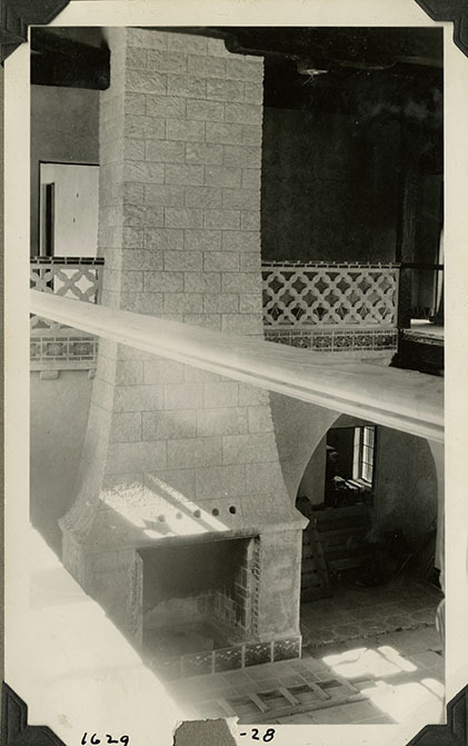 This is an historic black and white photograph from the Scotty's Castle Historic Photograph Collection, Death Valley National Park of fireplace in Scotty's Castle Main House Great Hall from Gallery during construction. Probably February, 1928. Photographed by Mat Roy Thompson.