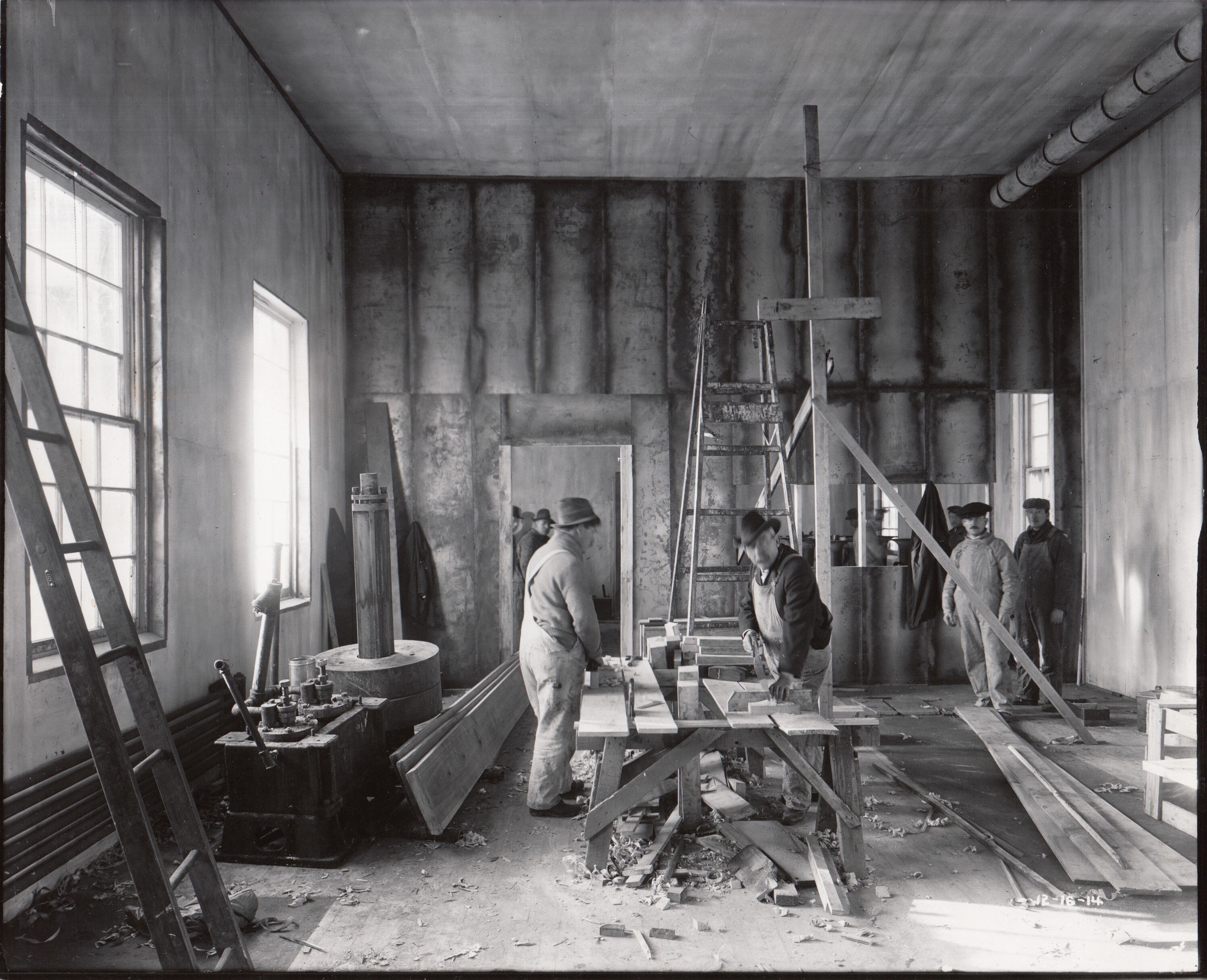Workmen sawing wood during reconstruction of Edison works.