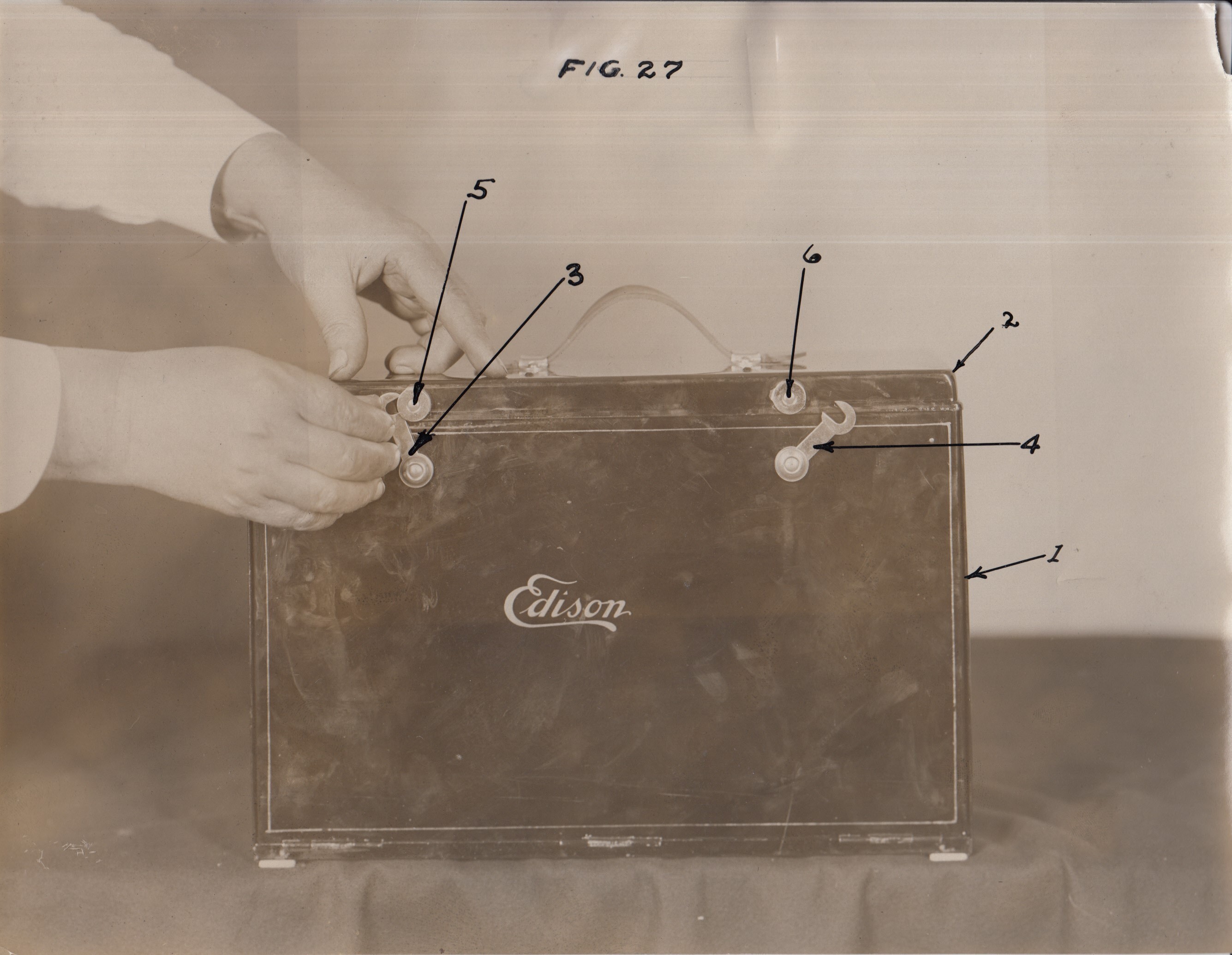 Edison home projecting kinetoscope, hands opening carrying case.