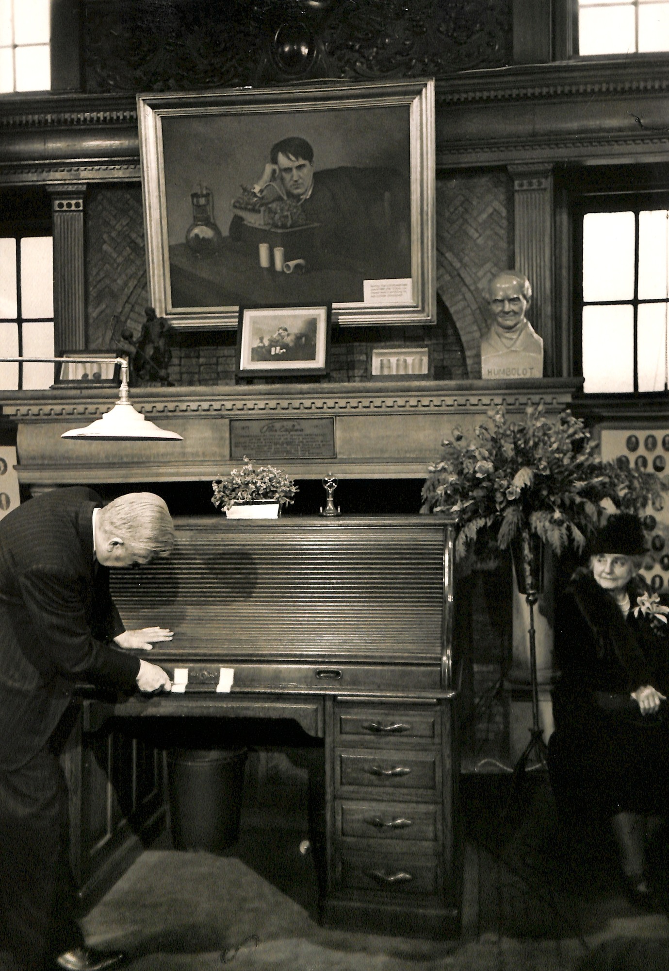 Charles Edison opening his father's desk in a ceremony in the library at the West Orange laboratory. Mina Edison at right.
