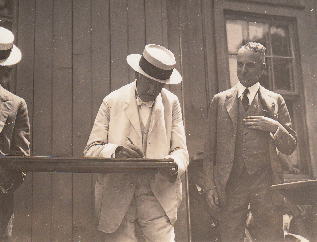 Thomas Edison and Henry Ford (obscured at left), autographing board at presentation of Glass House to Ford.