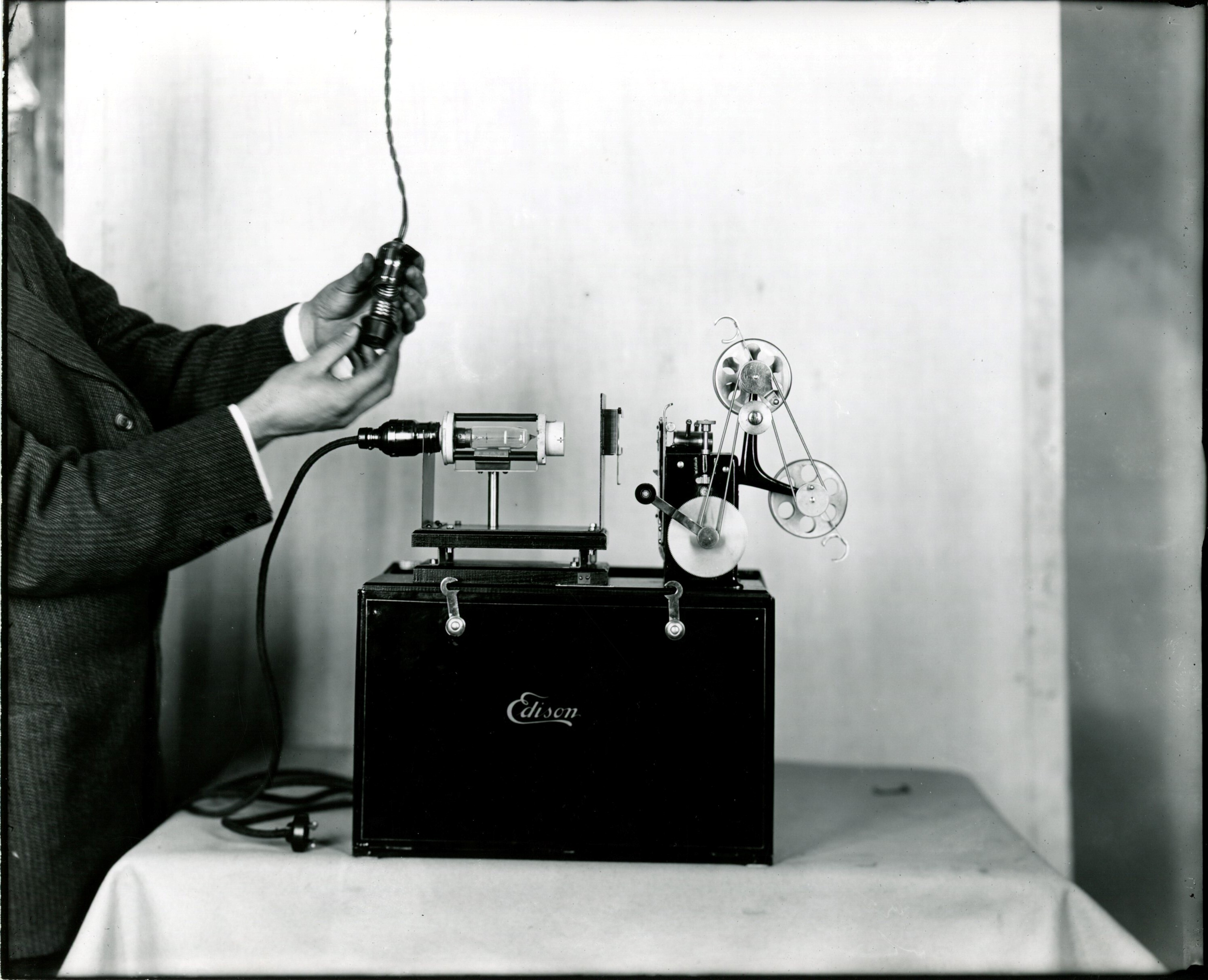 Edison home projecting kinetoscope, man attaching Nernst outfit.