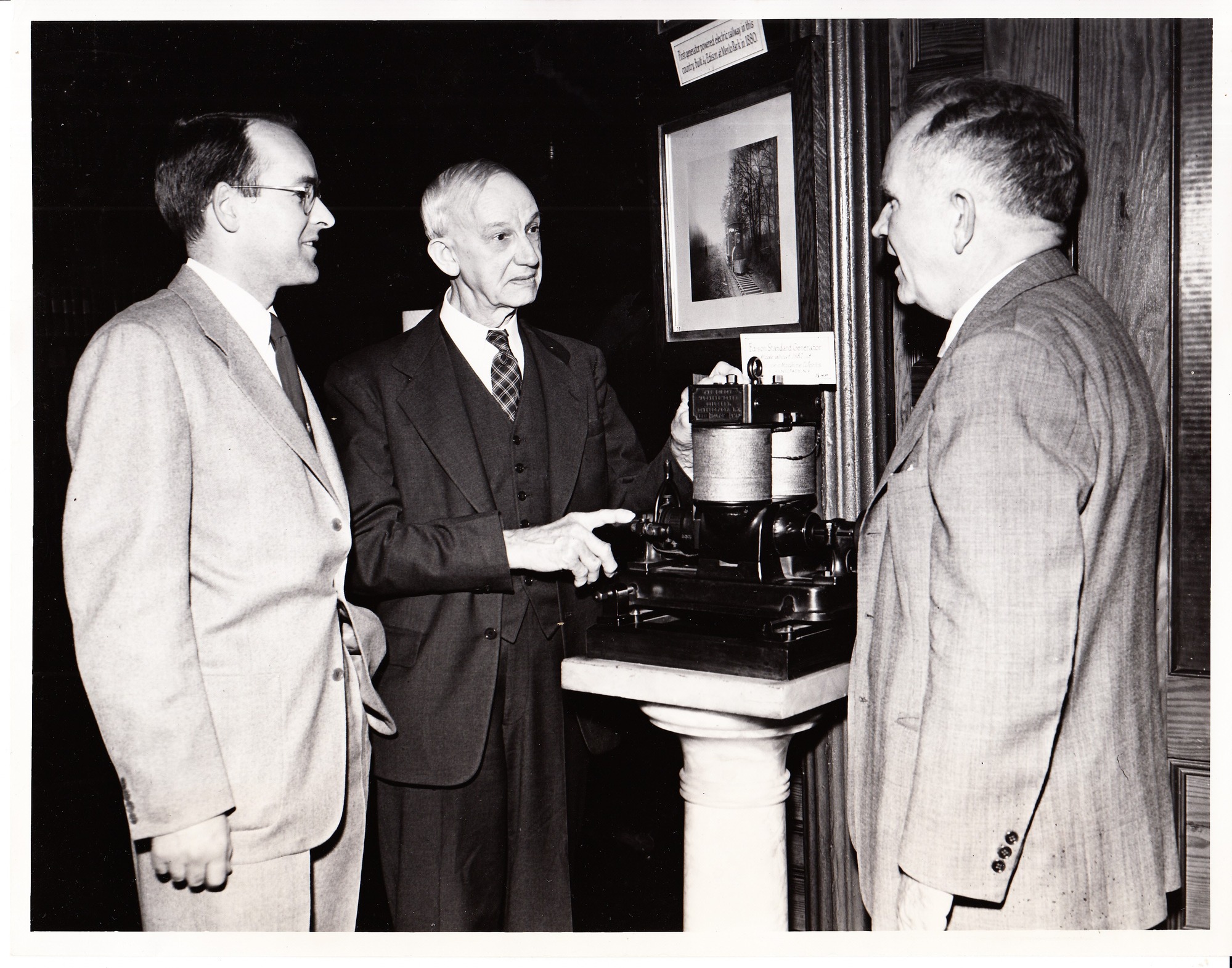 John T.H. Dempster, President of Edison Pioneers, examines model of generator with John E. Sloane, left, Thomas Edison's grandson, and Eugene Reel, Secretary of Edison Pioneers.