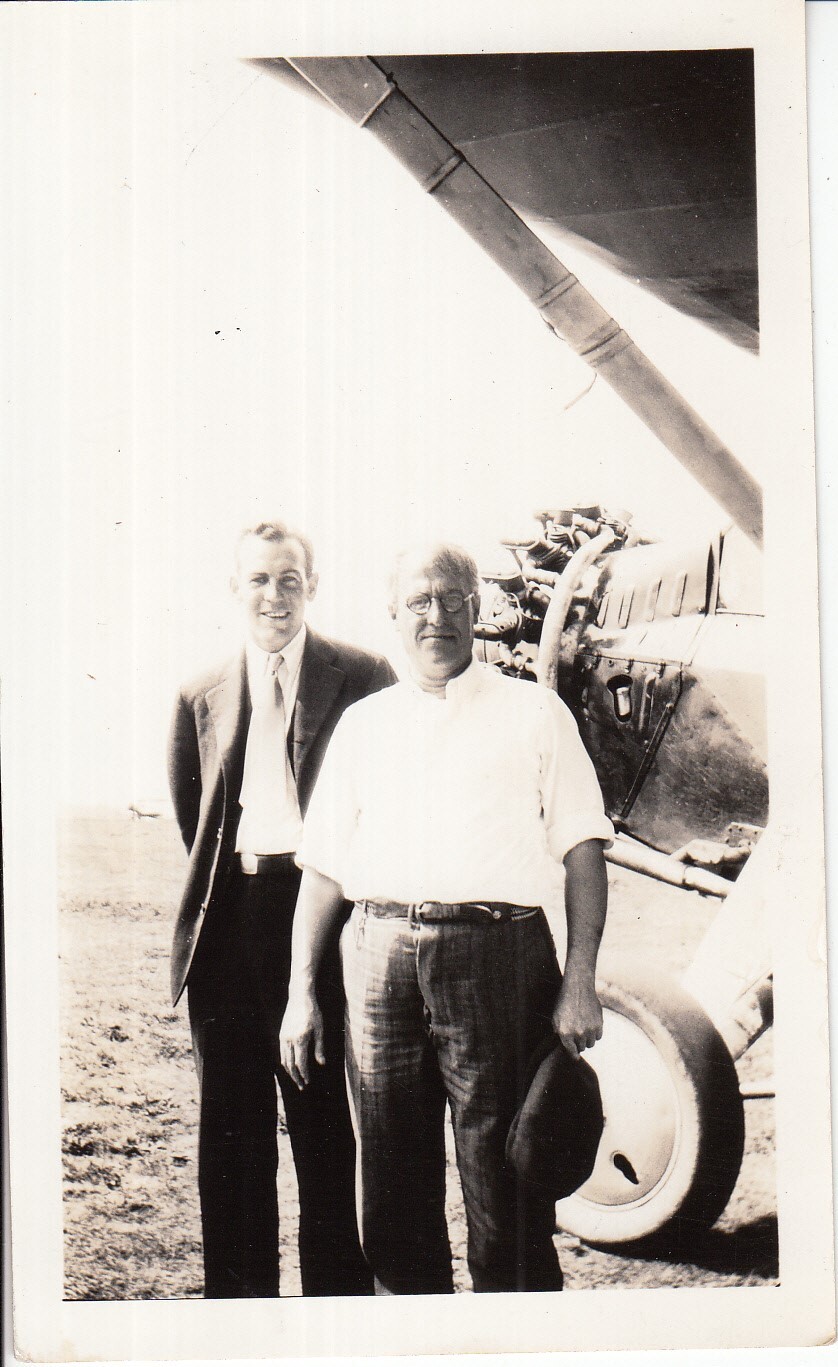 Two unidentified men standing in front of airplane.