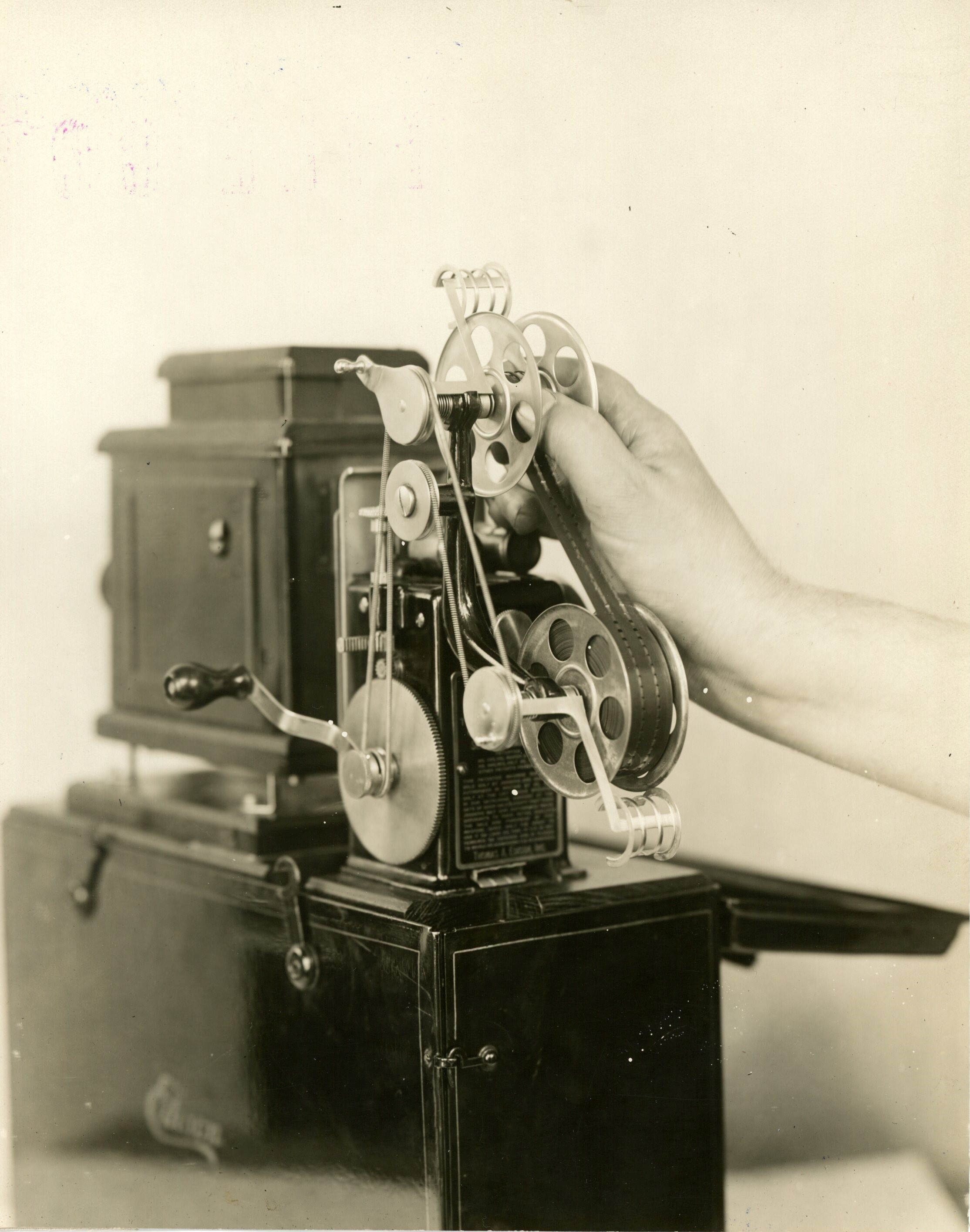 Edison home projecting kinetoscope, hand attaching film to upper reel.