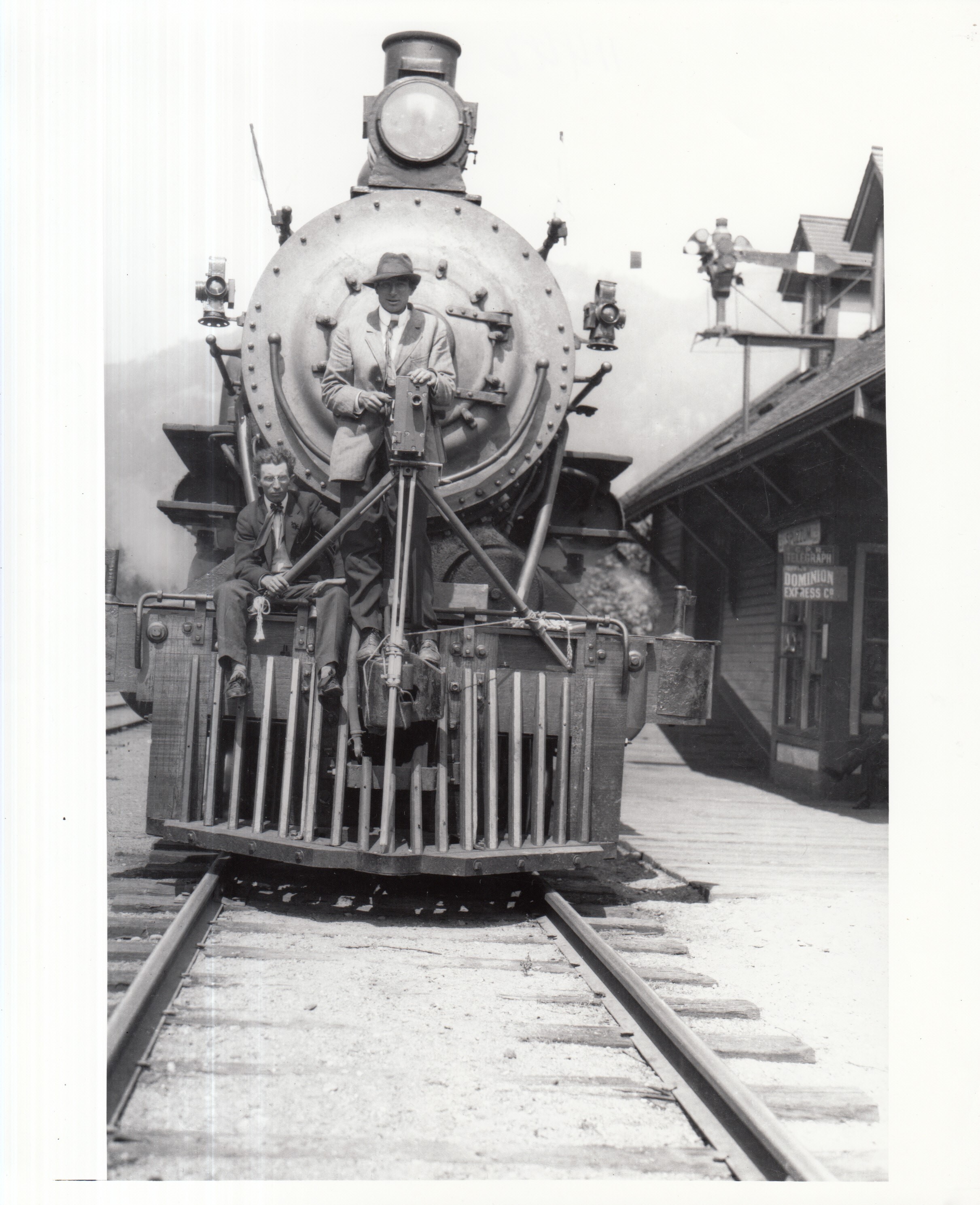 Edison co. motion picture-making expedition across Canada, J. Searle Dawley, director, left, and Henry Cronjager, cameraman, right, on cowcatcher of engine.
