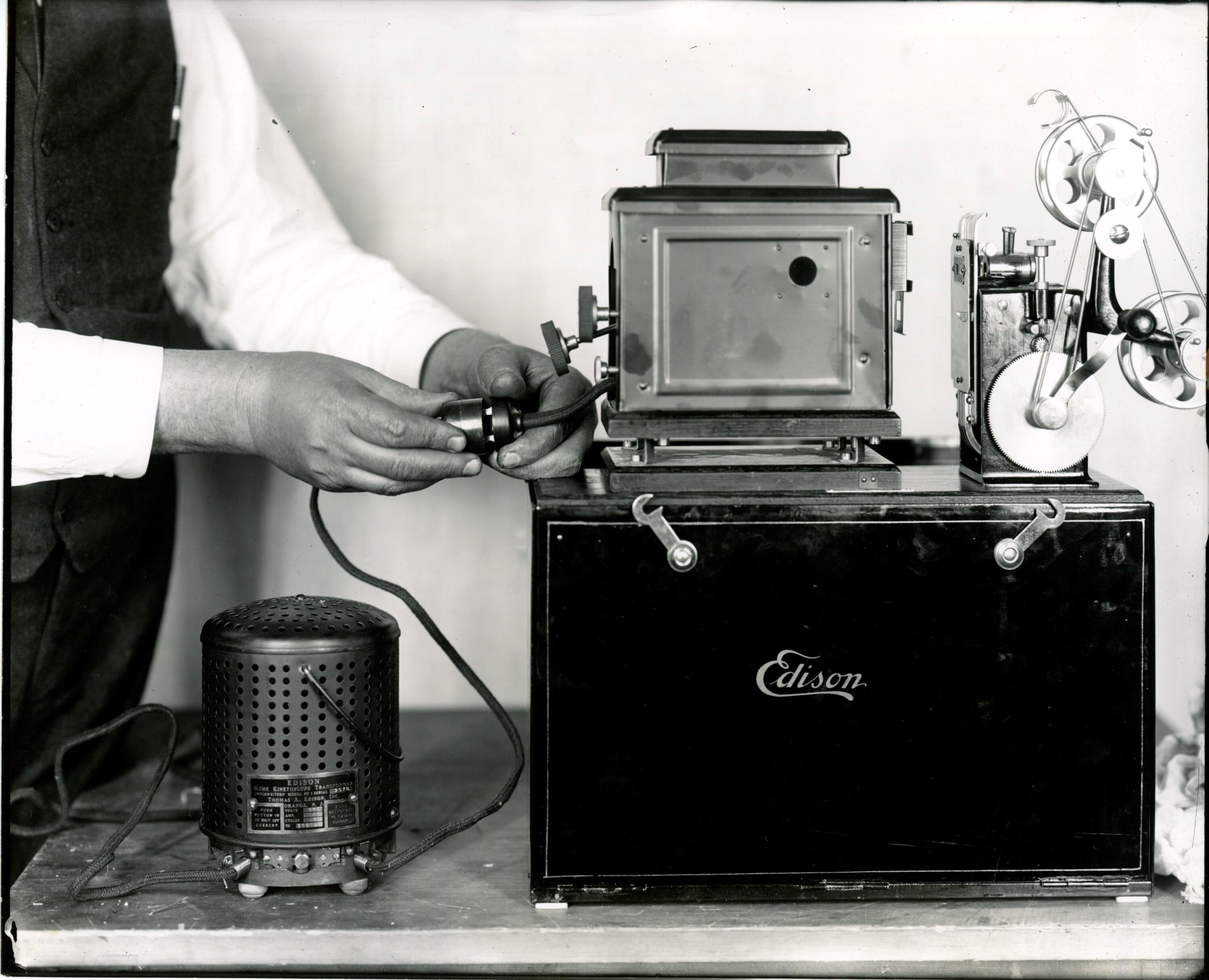 Edison home projecting kinetoscope, hands attaching transformer.