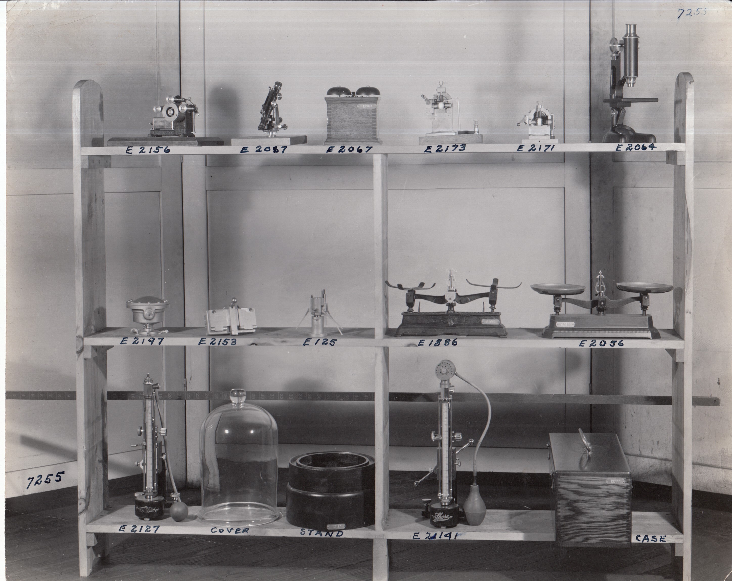 Edison artifacts displayed on shelves, including electric bells, microscope, scales, and bell jar.