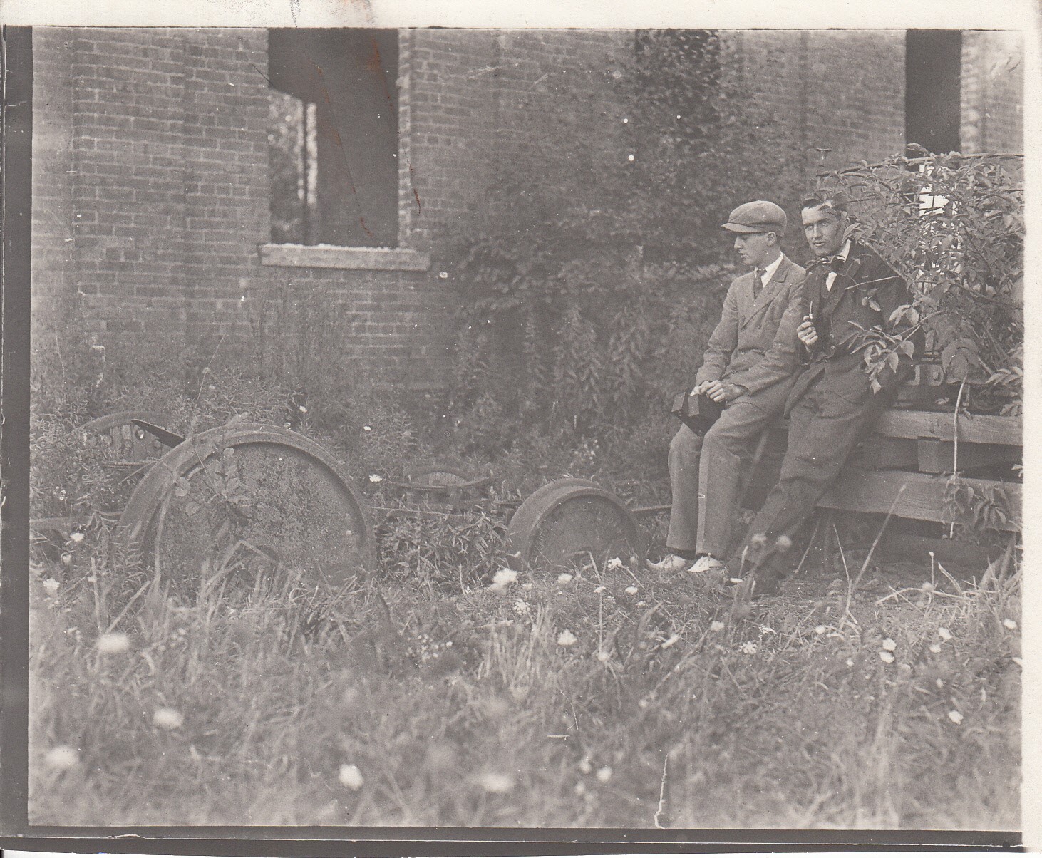 Theodore and Charles Edison sitting next to ruins of electric locomotive near machine shop at Menlo Park lab.