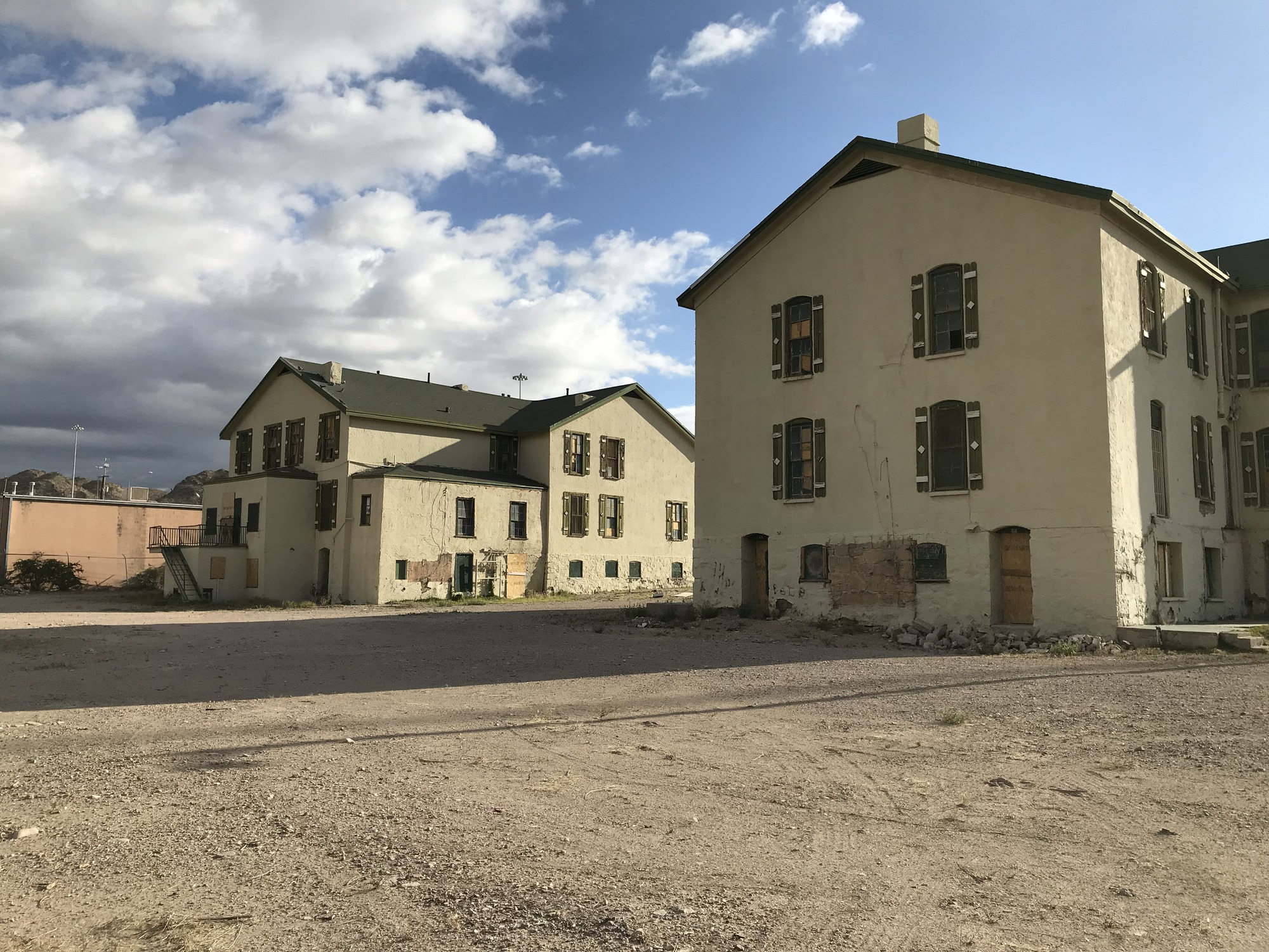 Two old buildings in a desert with a cloudy sky.
