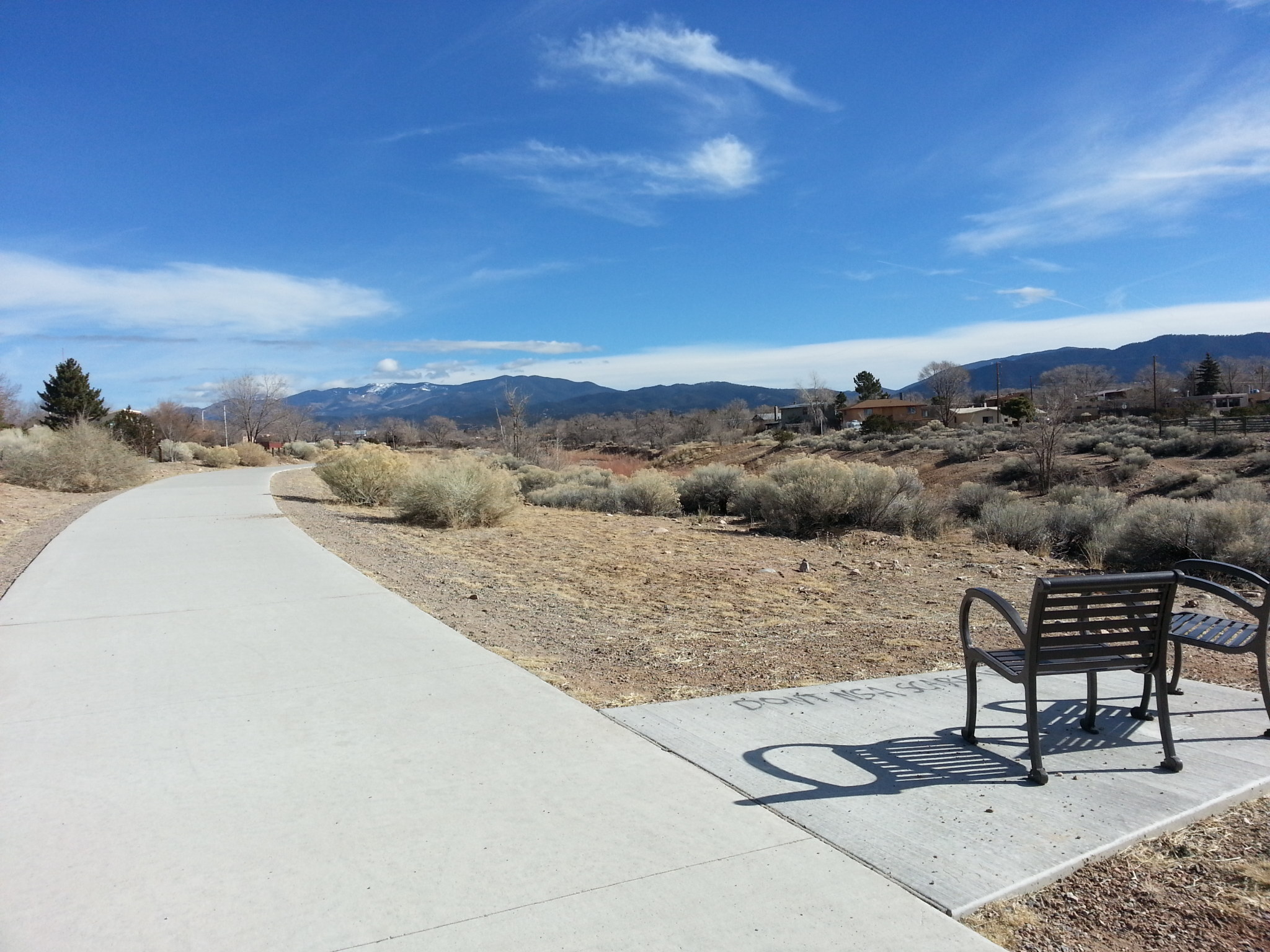 A bench on a sidewalk next to a mountain.