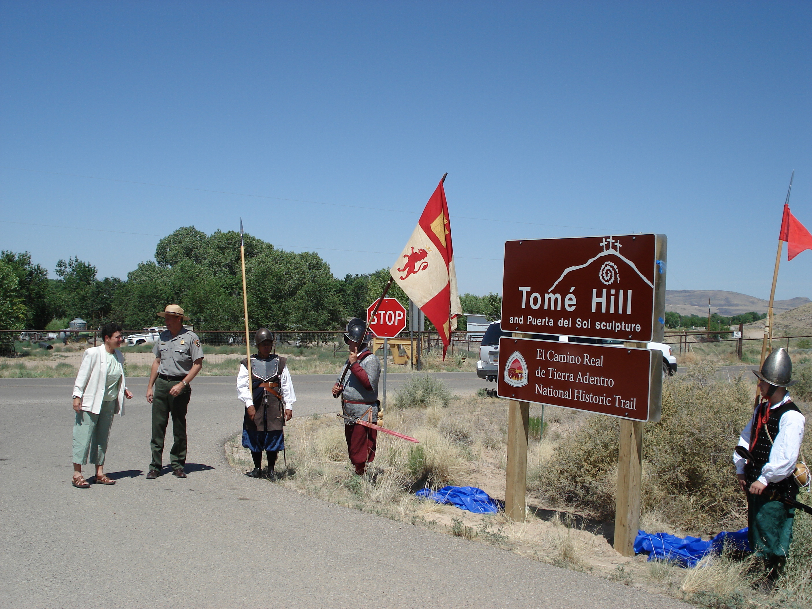 A group of people standing in front of a sign which has text "Tome Hill" on it.