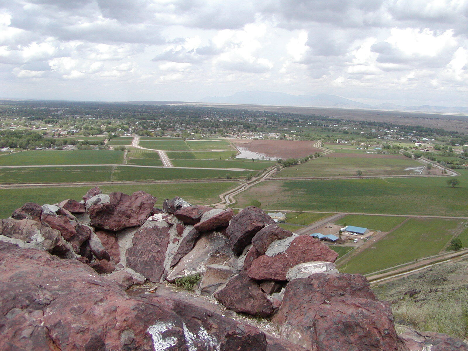 A view of a field and a large rock.