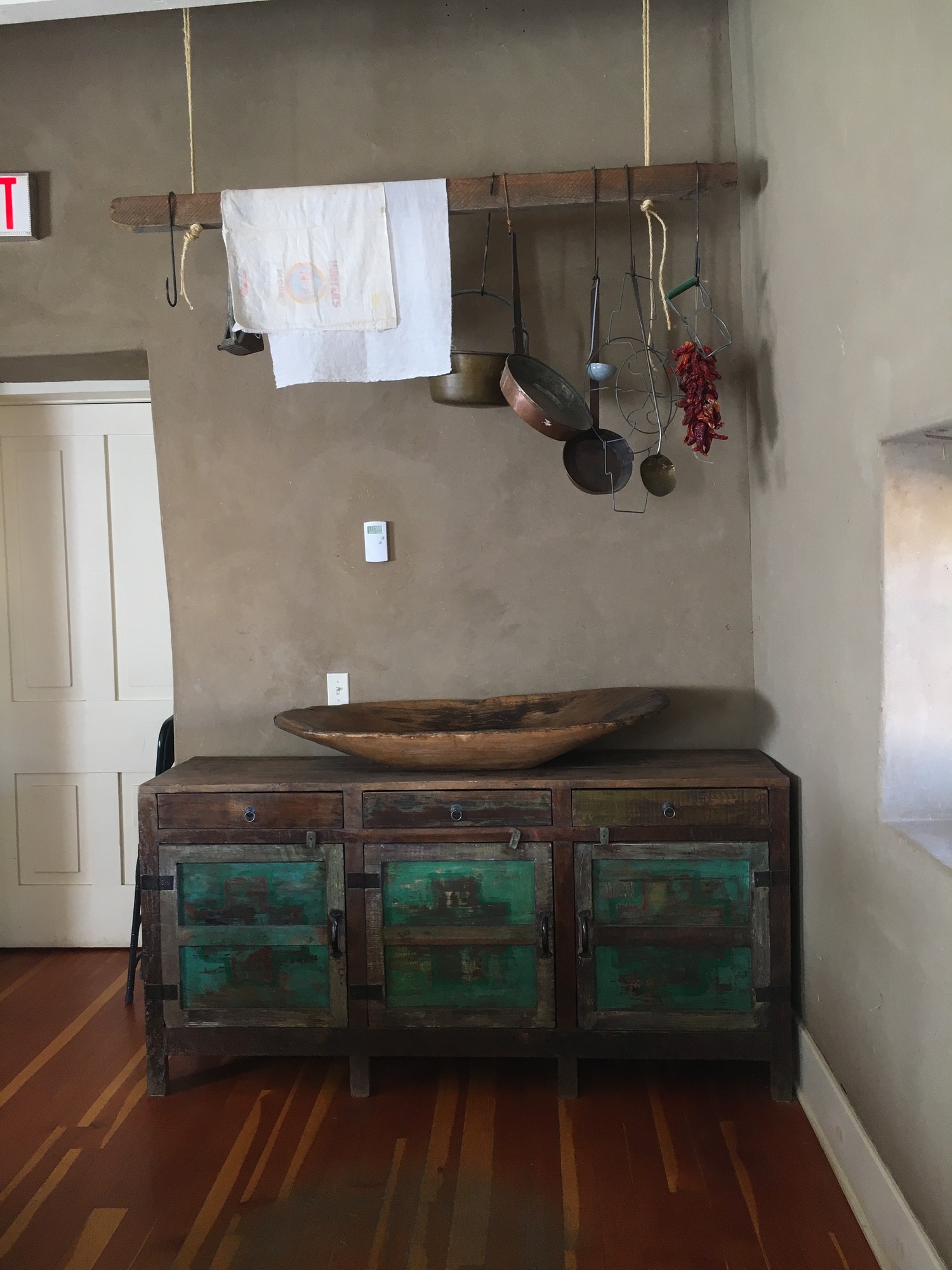 A wooden cabinet with pots and pans hanging from it.