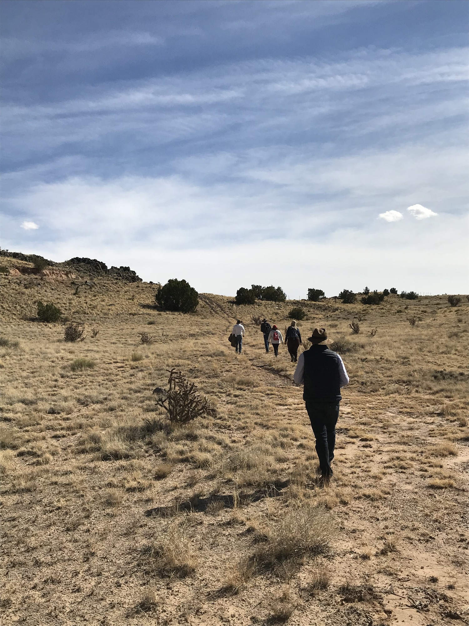 A group of people walking on a trail in the desert.