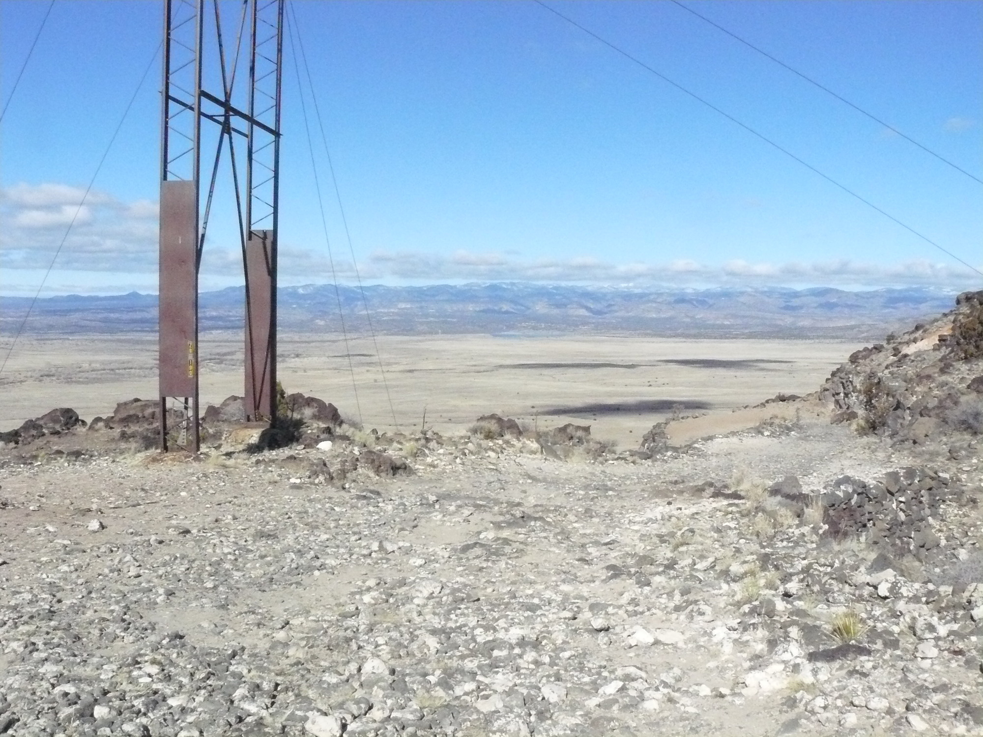 A view from the top of a mountain with a structure in the distance.