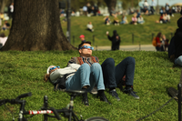 Two people sit on a grassy hill wearing protective eyewear to enjoy a partial solar eclipse