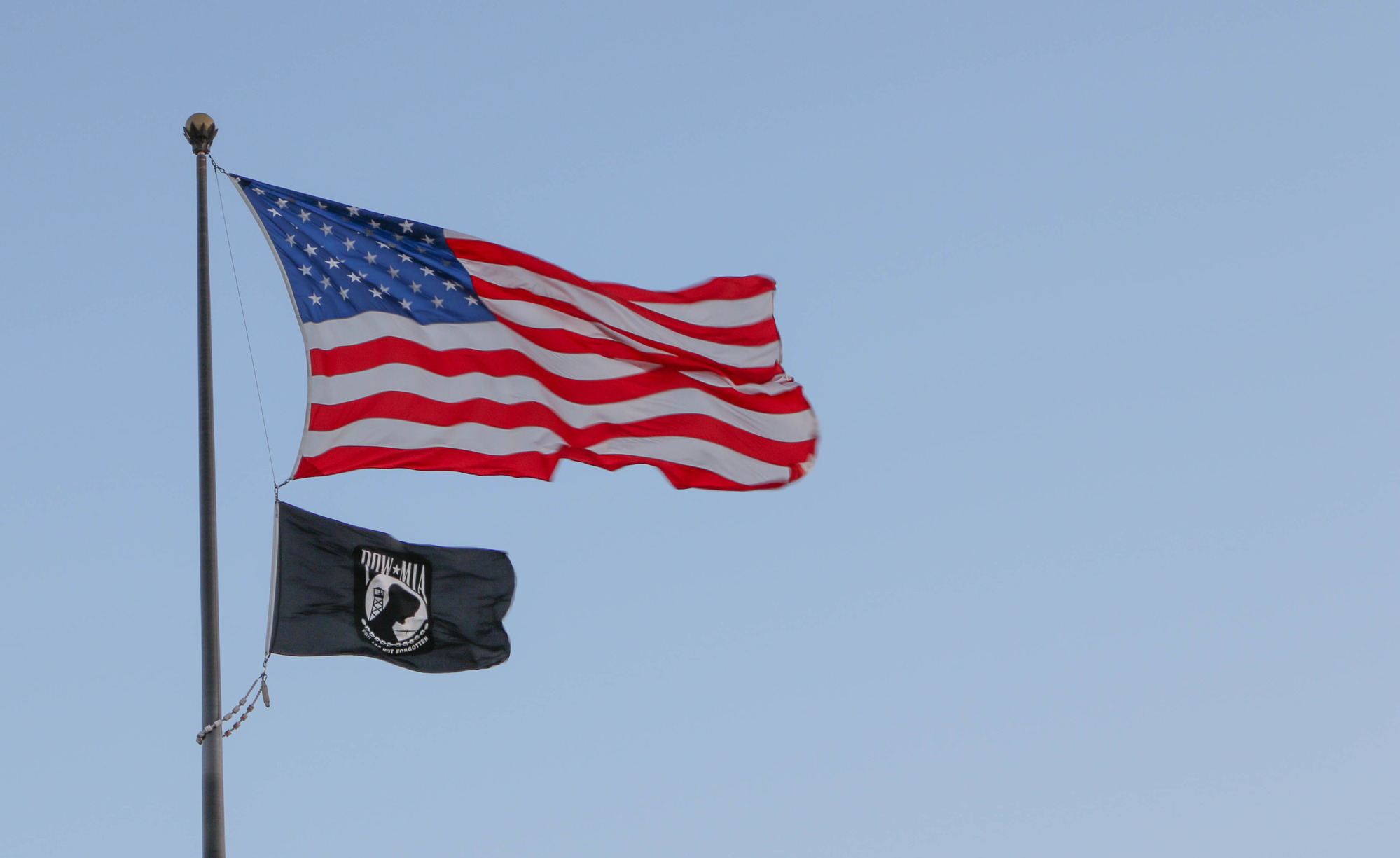 U.S. flag and P.O.W. flag flying in the wind