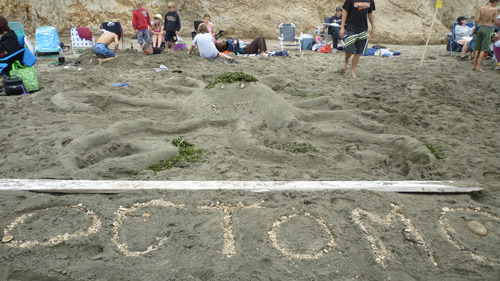 A sand sculpture of an octopus with small rocks in the foreground spelling out Octomom.