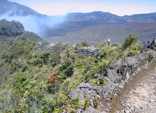 Low clouds hang in the expansive crater, surrounded by hills under a clear sky.
