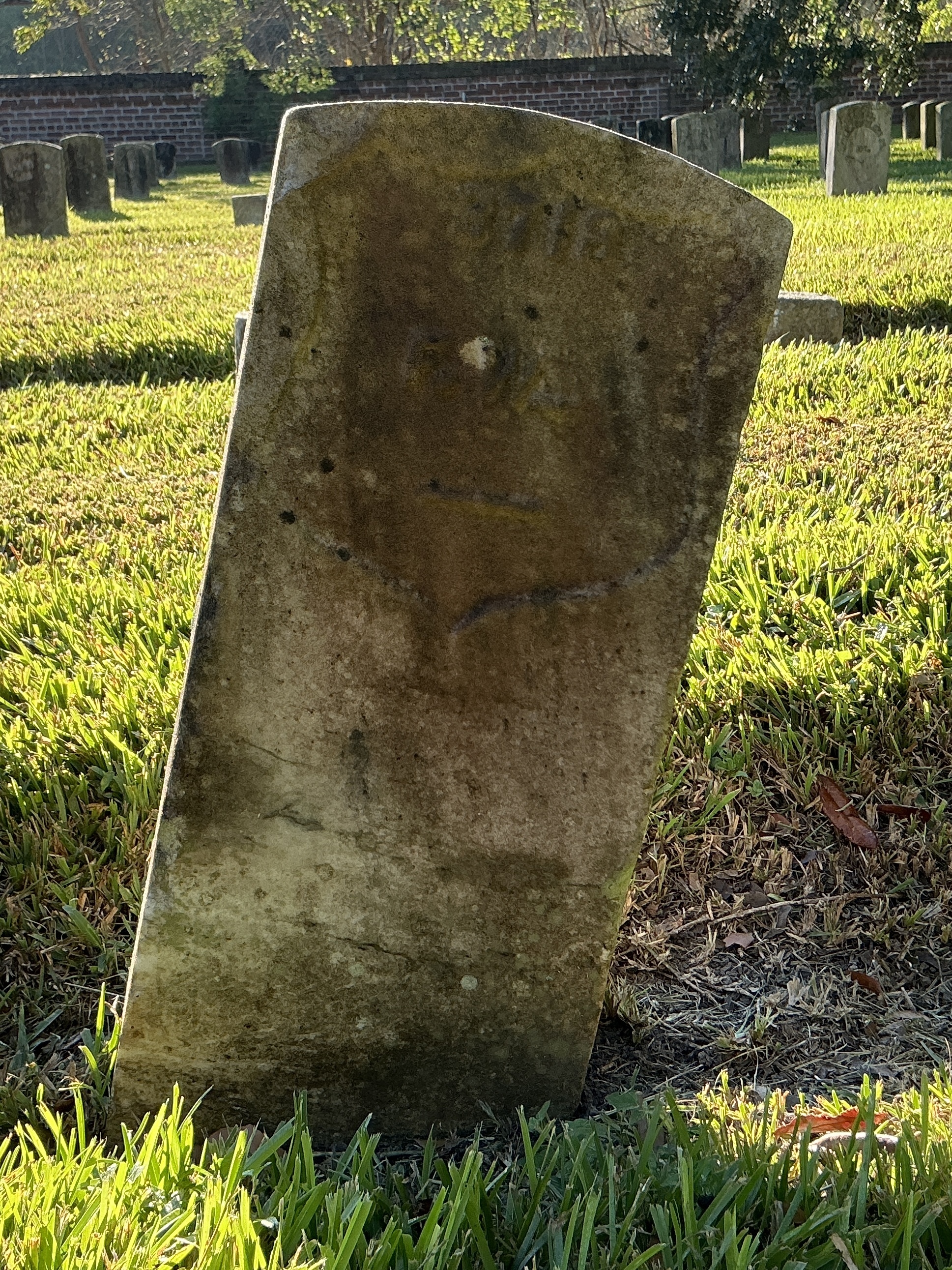 Front of historic upright marble headstone with recessed shield face.