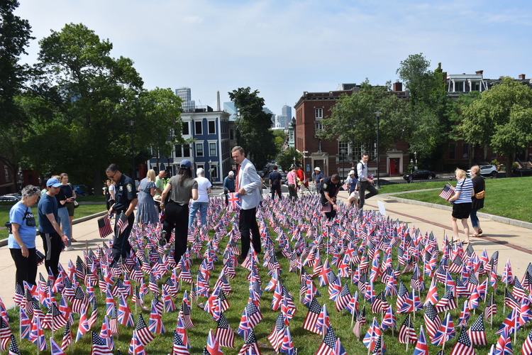 People walking amidst rows of small US and UK flags.