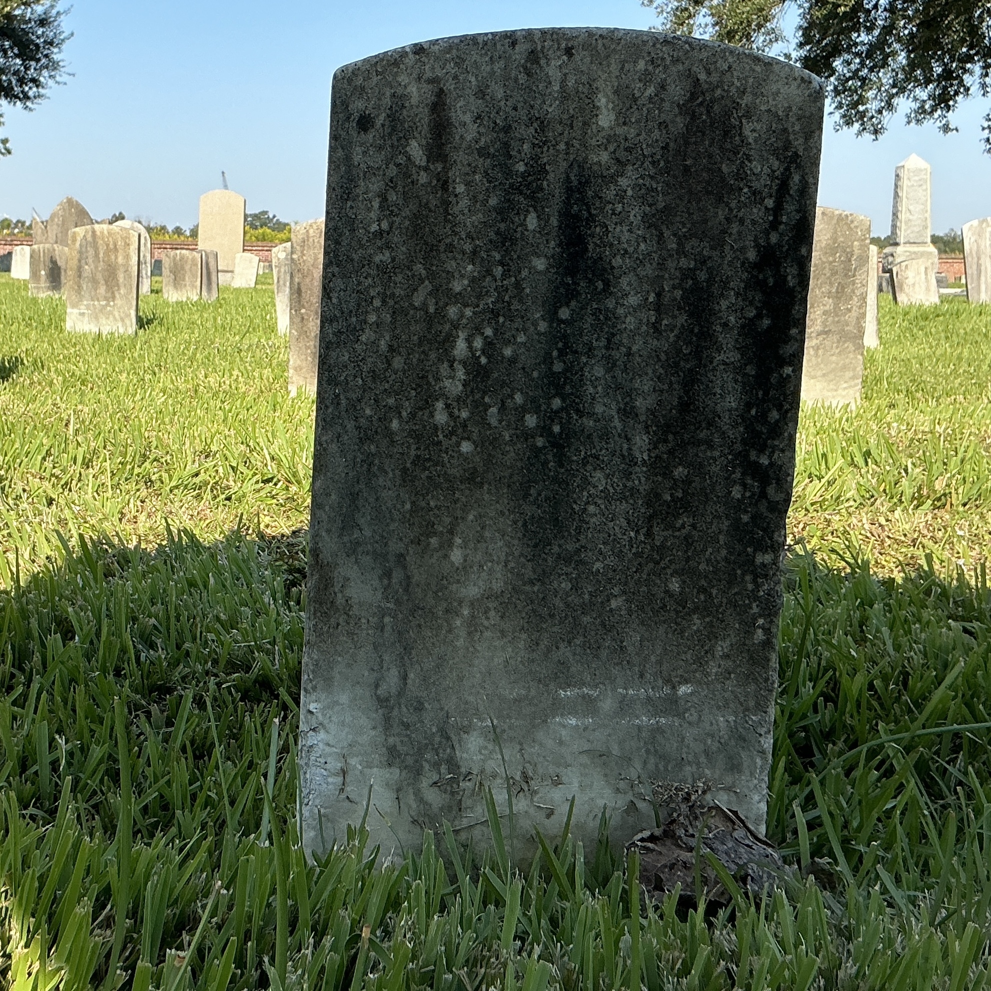 Back of historic upright marble headstone with recessed shield face.