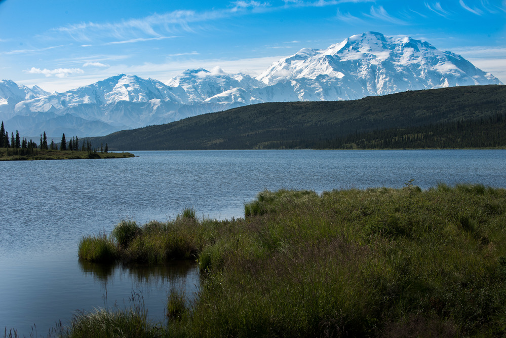 A landscape of hills, forests and a huge, snowy mountain