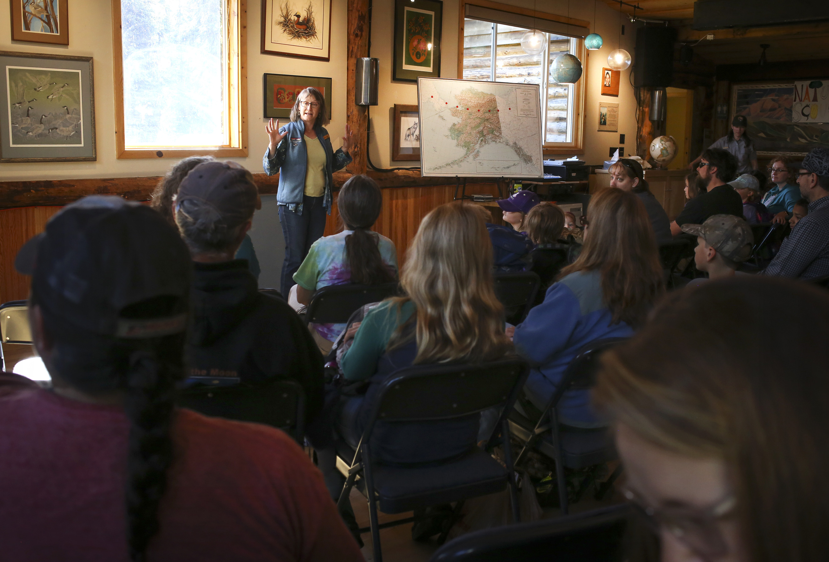a woman speaking to a group of seated kids