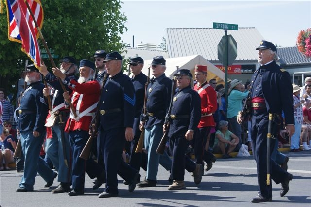 National park volunteers march down Spring Street for the Fourth of July Parade in Friday Harbor as Park Ranger Mike Vouri calls cadence to keep everyone marching in time. The British and American's are marching together to demonstrate the peaceful joint occupation of this island in the 1860s.