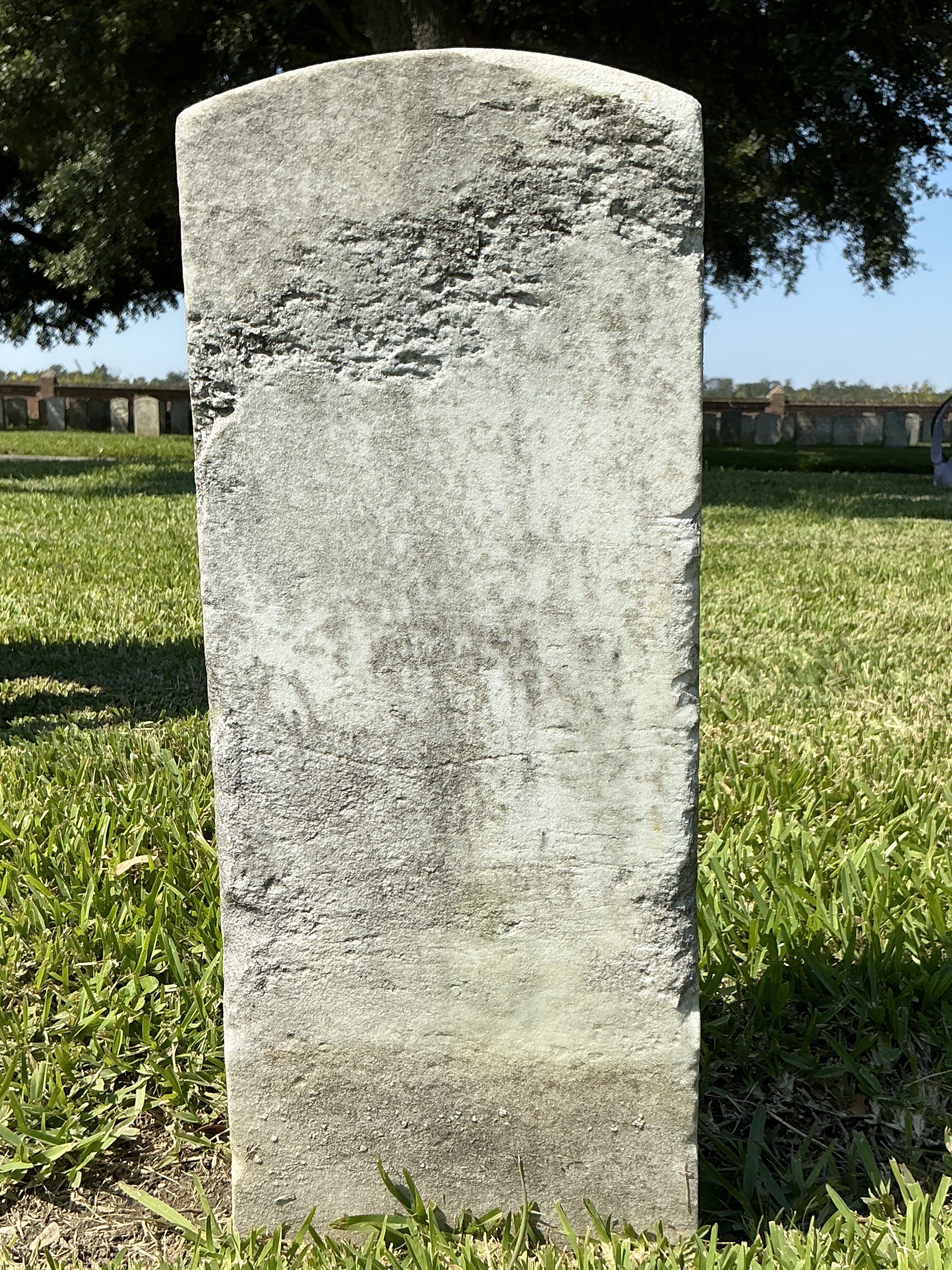 Back of historic upright marble headstone with recessed shield face.