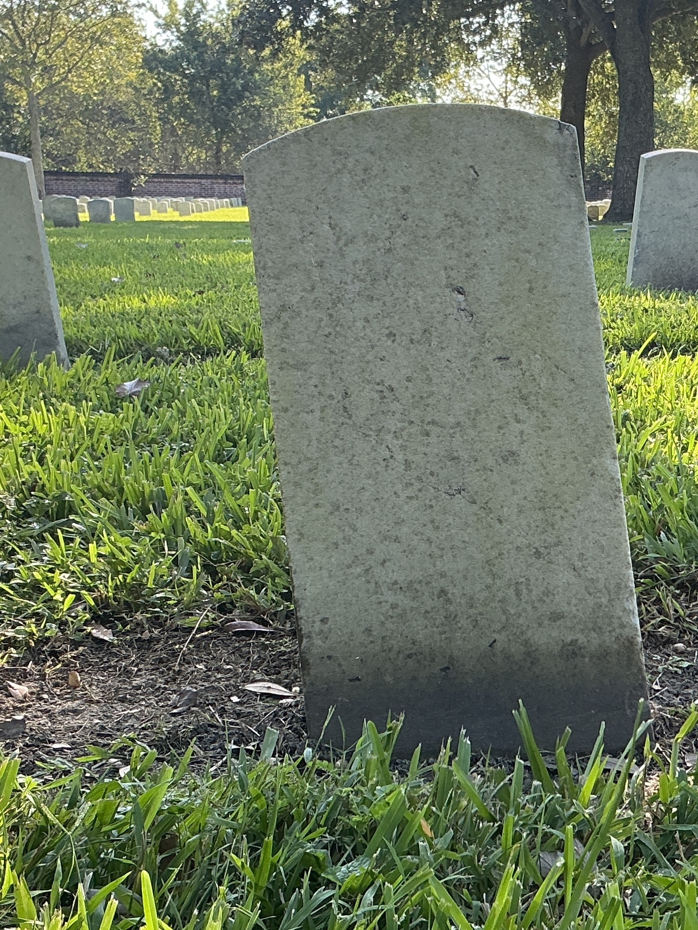 Back of historic upright marble headstone with recessed shield face.