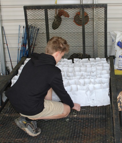 A young man is squatting on a trailer and aligning lunch bags.