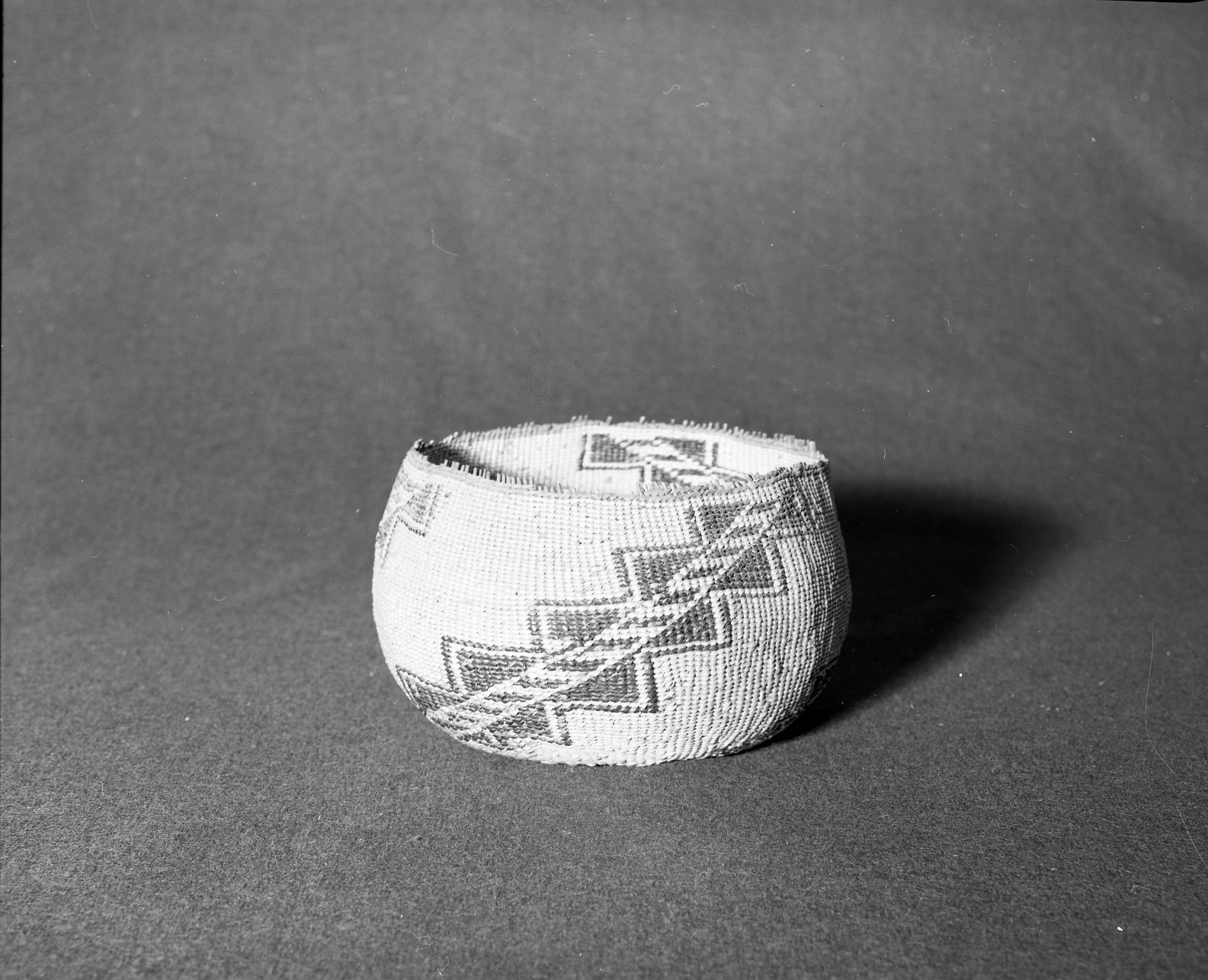 Marie Rozier Collection, Catalog No. 102. Object: Atsugewi basket. Wintu? Dimensions: 8" x 5". Materials: conifer root, bear grass, maidenhair fern stem. Technology: three bands of three strand twining at start similar to documented Wintu pieces; up to right slant of turns. Collection History: Alice Reade Collection. Photographed by Michael Dixon, December 1982. Catalogued by Craig Bates and Barbara Beroza. Yosemite Collections, National Park Service.