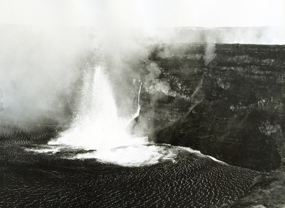 Lava fountains and steam clouds on the floor of a volcanic crater.