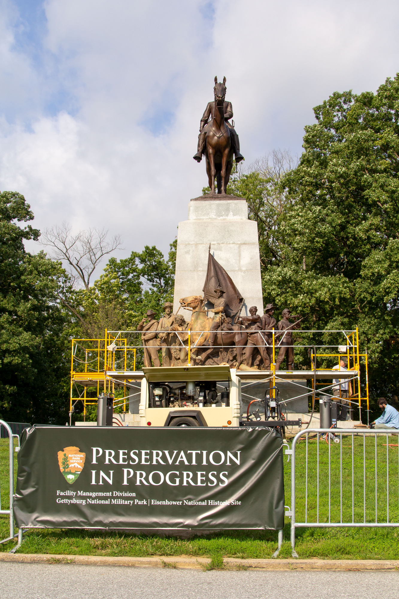 A Civil War statue with tall stone base, soldiers on the bottom and an officer on horseback on top. The statue is surrounded by scaffolding and a fence with a sign "Preservation in Progress"