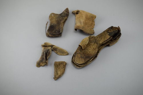 Pieces of a brown leather work boot with brass rivets.