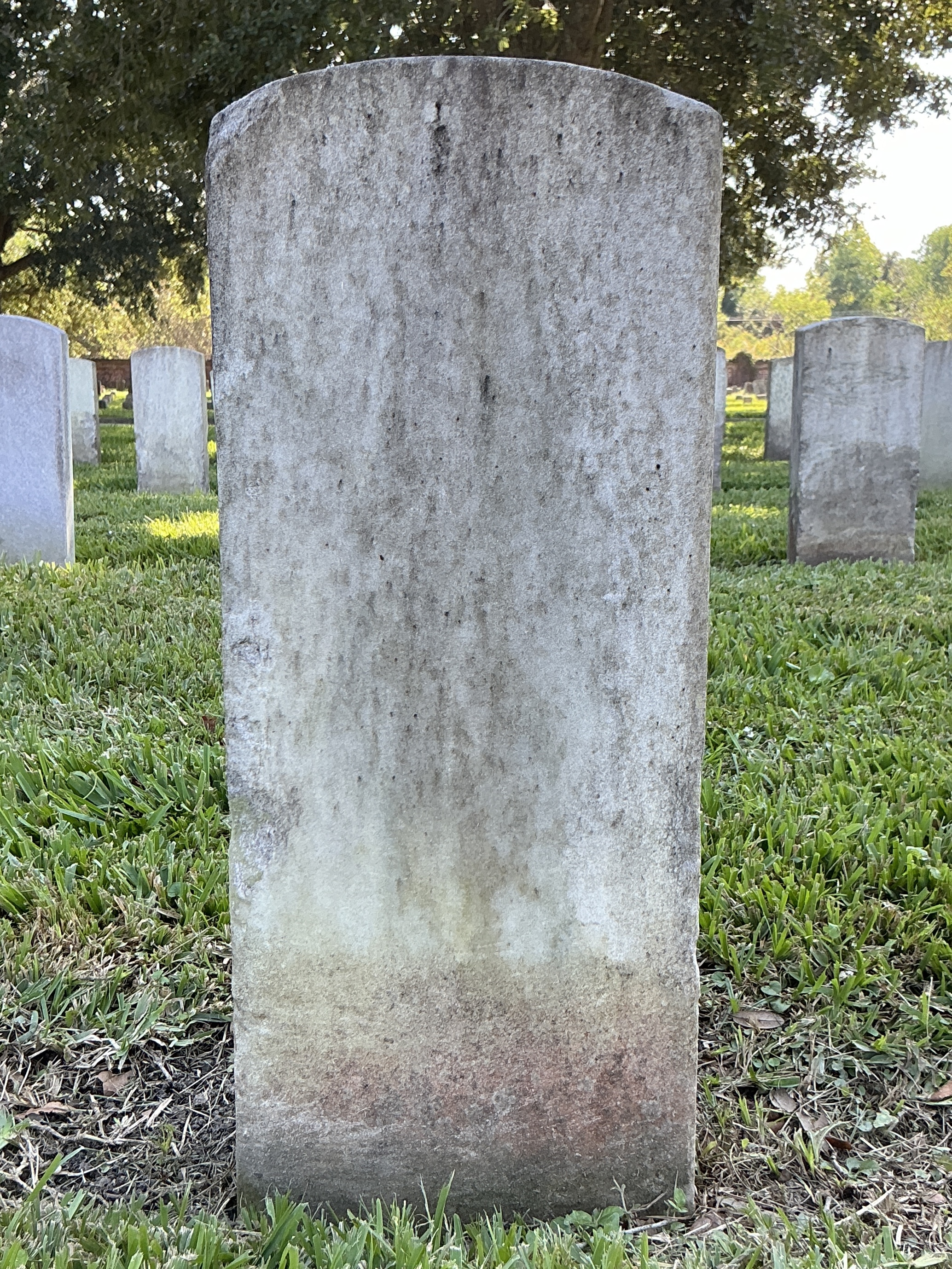 Back of historic upright marble headstone with recessed shield with recessed lettering face.