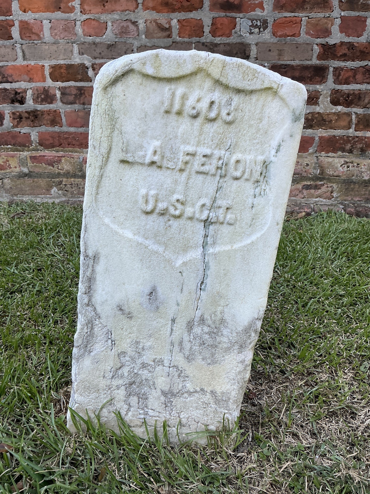 Front of historic upright marble headstone with recessed shield face.