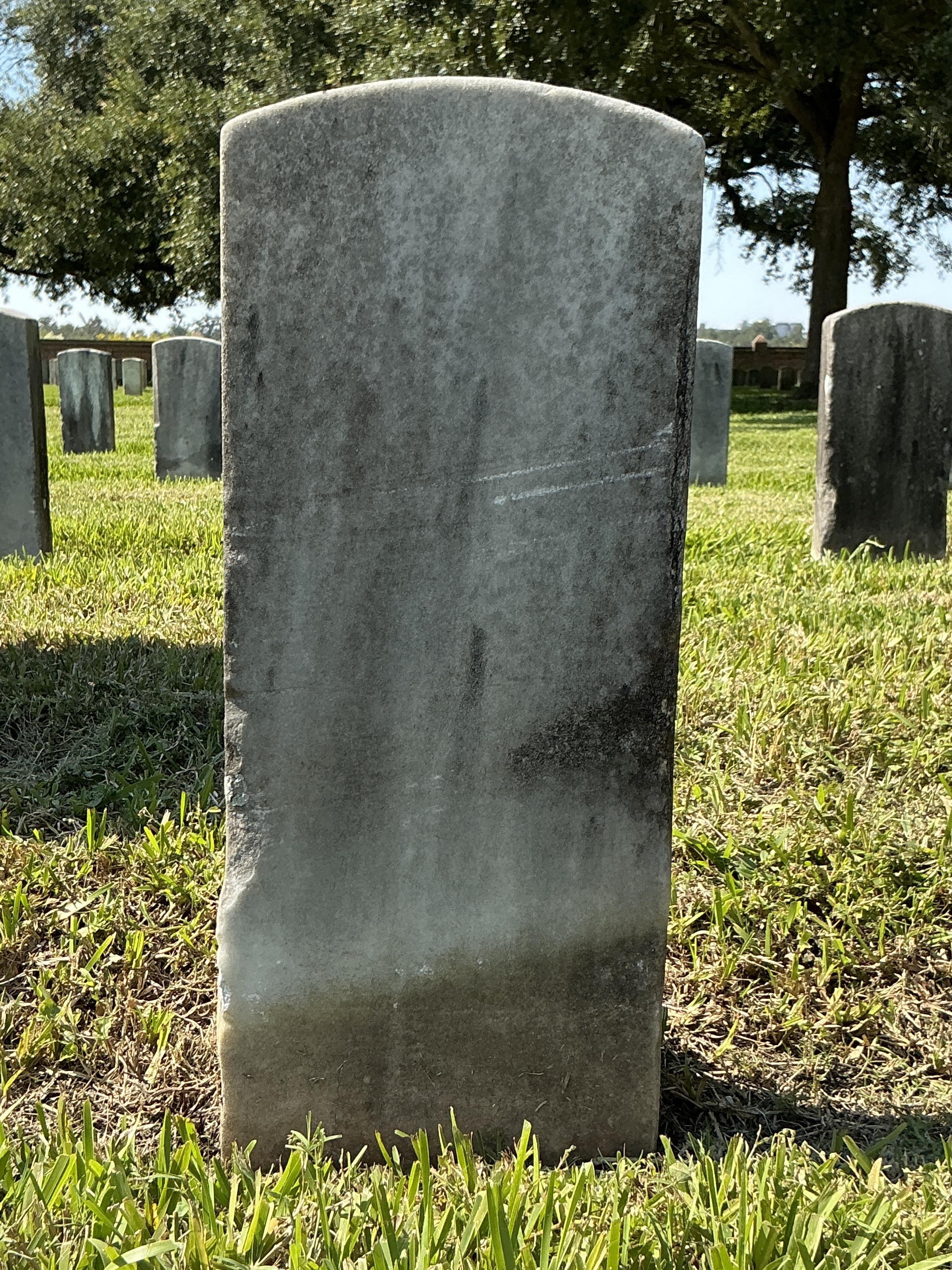 Back of historic upright marble headstone with recessed shield face.