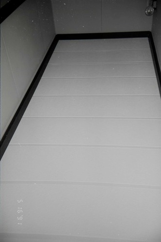 Ceiling at end of hallway in barracks, light fixture visible in corner. [Image possibly for comparative housing study]