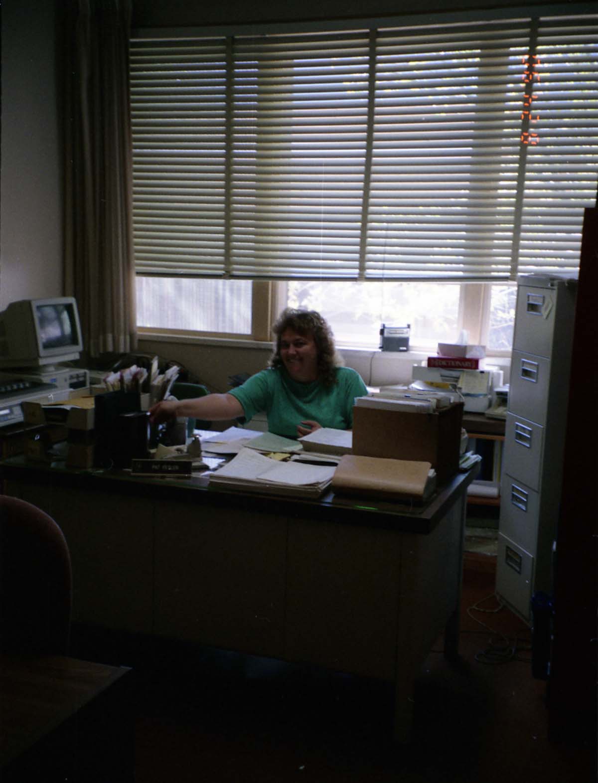 Color Photos of administration personnel. Woman seated at desk.