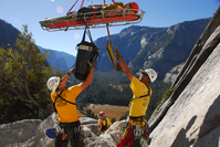 Search and Rescue crew coordinates with helicopter lifting patient from rock face
