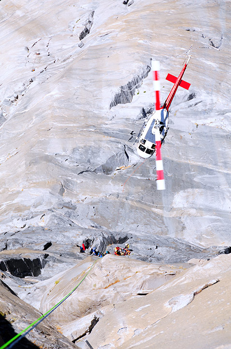 view looking down at a search and rescue helicopter flying over people in a canyon