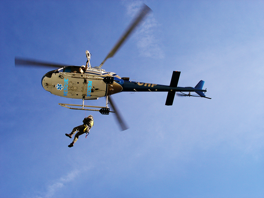 ranger hanging from a search and rescue helicopter, bottom view of helicopter