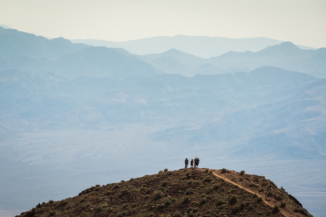 Four distant people on a hill in the distance, with hazy mountains in the background.