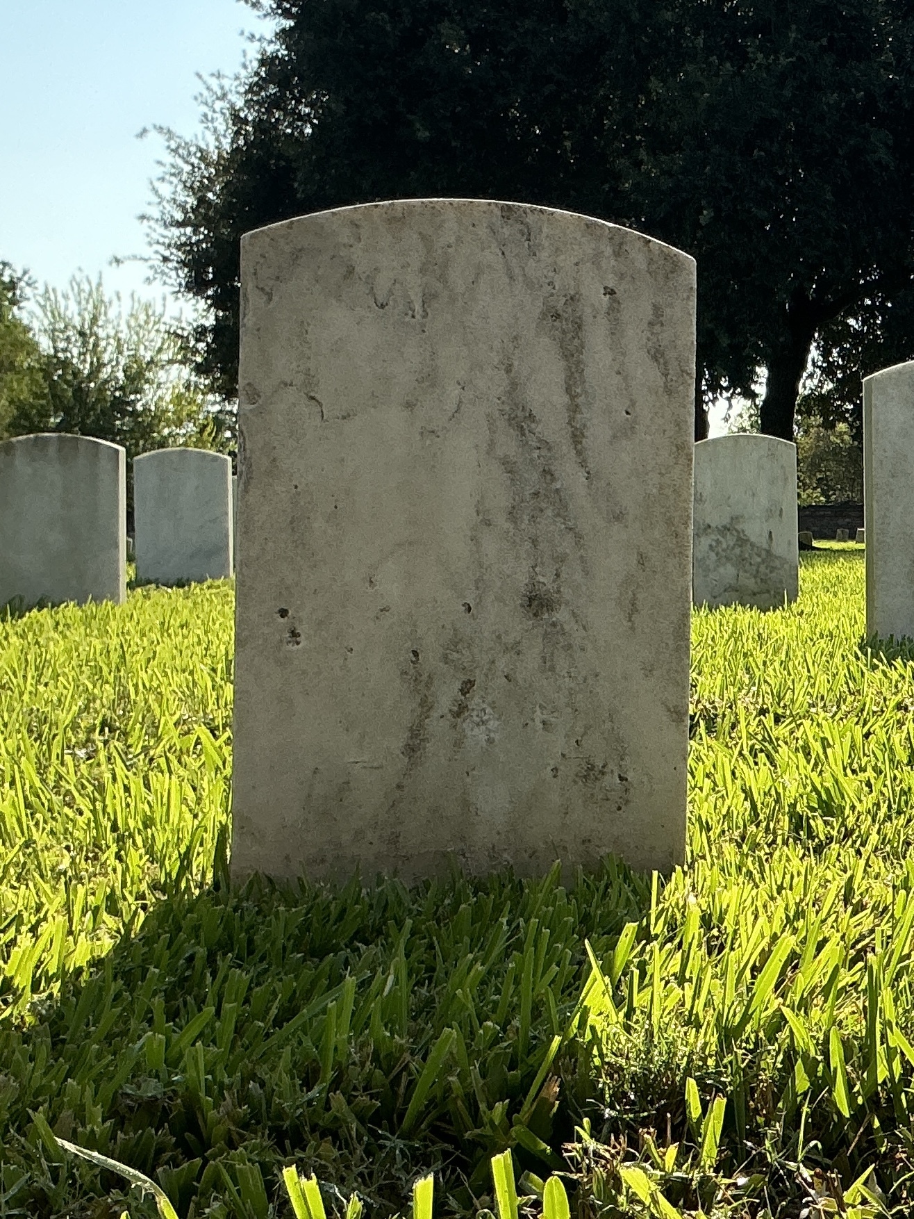 Back of historic upright marble headstone with recessed shield face.