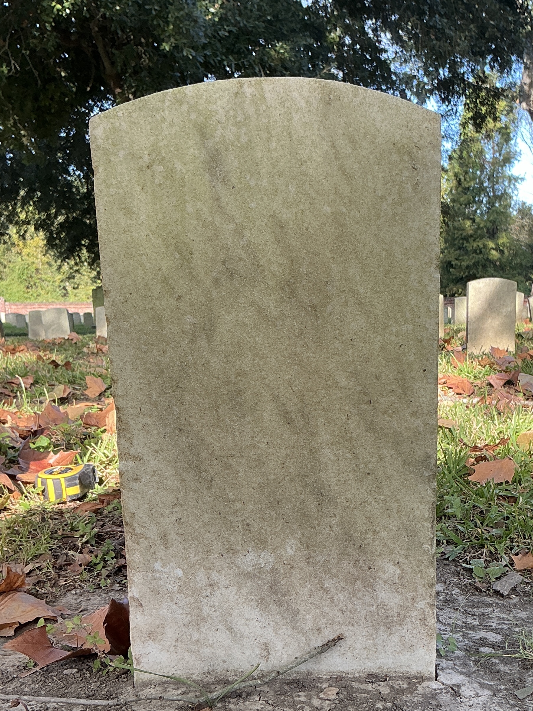 Back of historic upright marble headstone with recessed shield face.
